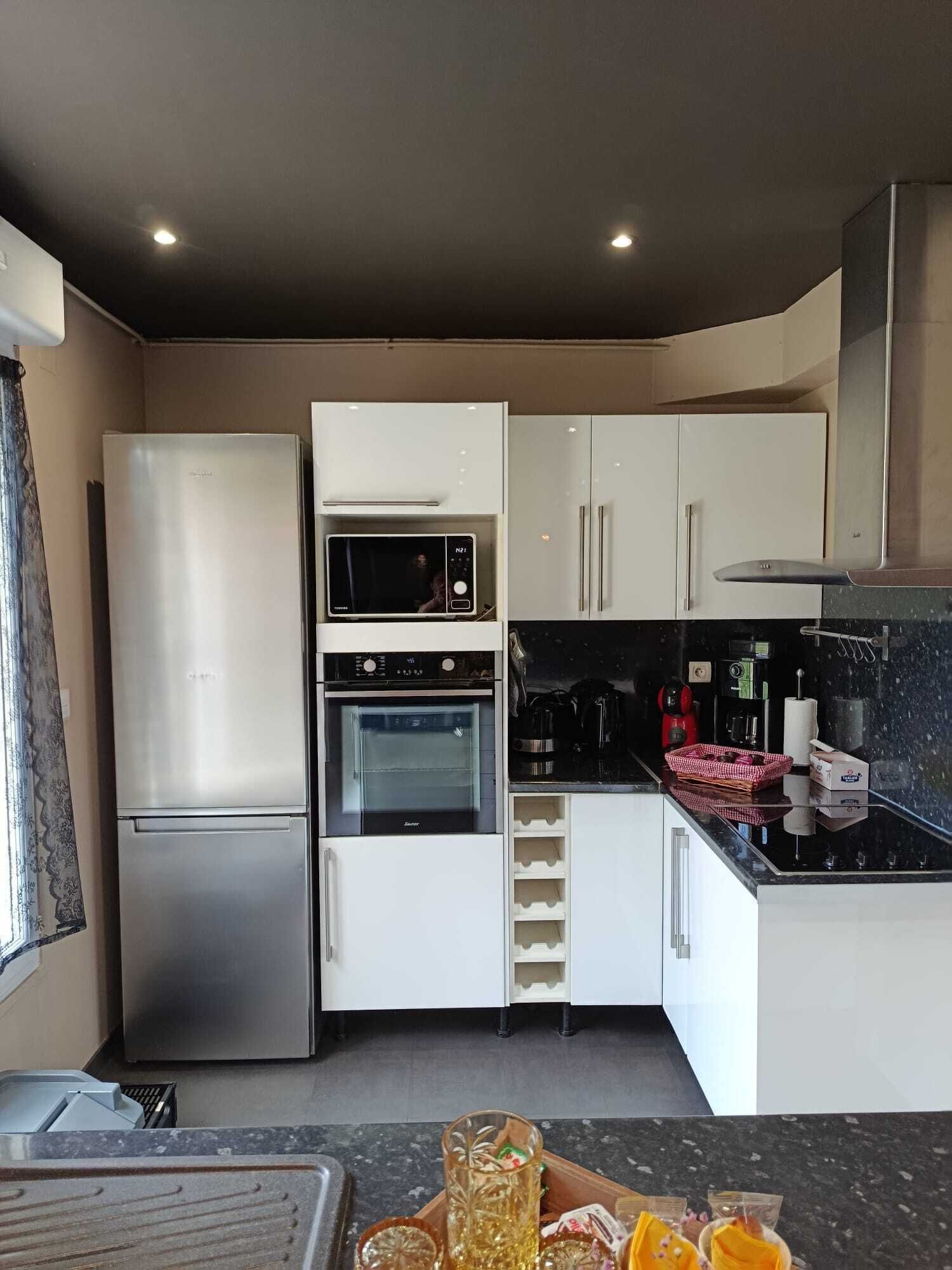 Uma cozinha compacta com geladeira, micro-ondas, forno e cafeteira.