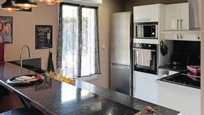A modern kitchen with a black countertop, stainless steel appliances, and pendant lighting.