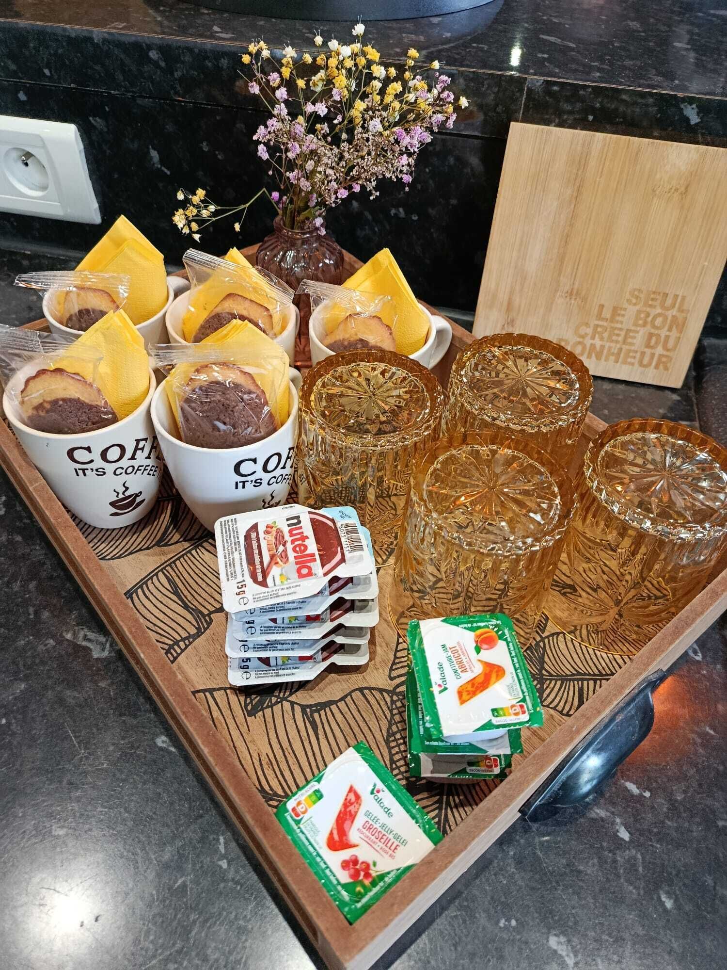 Un vassoio con tazze da caffè, vasetti di Nutella e bicchieri su un piano di lavoro della cucina.
