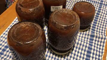 Five glass jars with a dark liquid on a blue and white checkered cloth.