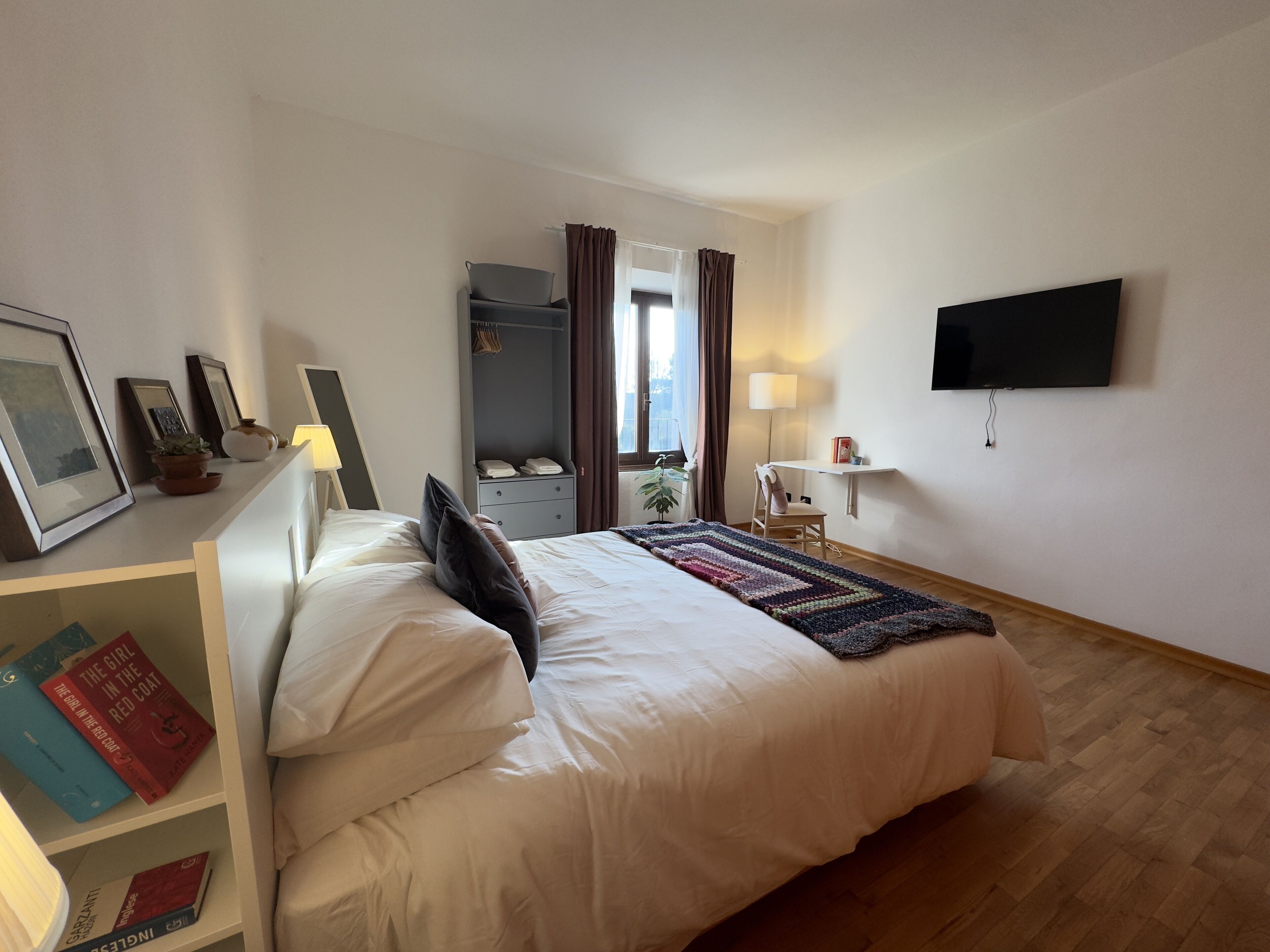 Une chambre d’hôtel comprenant un lit, un bureau, une chaise, une télévision et une armoire.