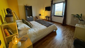 A bedroom with a bed, bedside table, lamp, and a view of the city through a window. - Affittacamere Ca' da Mazapedar (Lugo)
