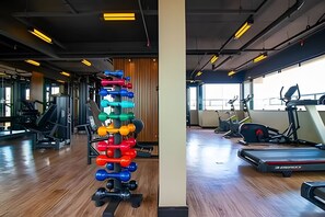 A gym with exercise equipment, wooden flooring, and large windows.