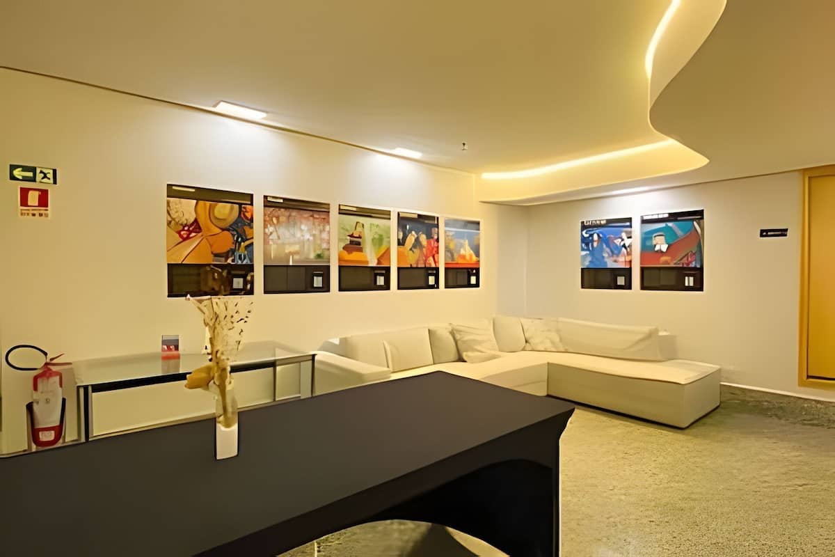 A modern hotel lobby with a reception desk, a white sofa, and artwork on the walls.