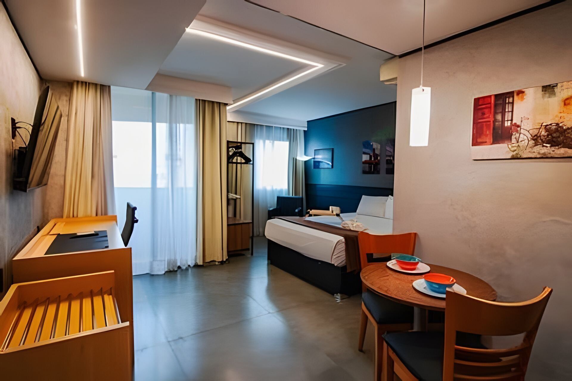 Une chambre d’hôtel moderne équipée d’un lit, d’un bureau, d’une chaise et d’une table à manger.