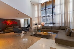 Una sala de estar moderna con un ventanal amplio, un sofá, sillones y una obra de arte abstracta roja en la pared.