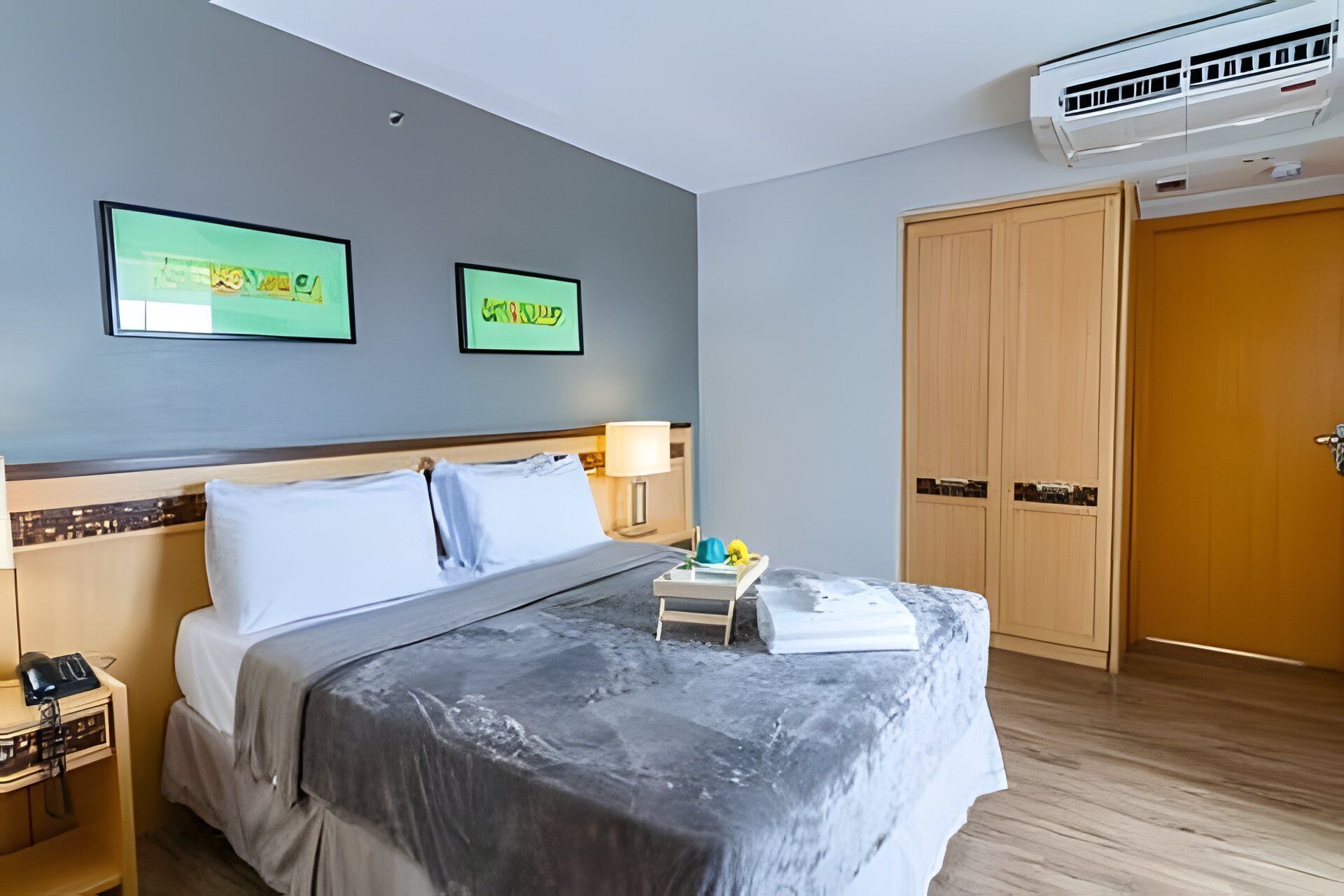 Une chambre d’hôtel équipée d’un lit, d’une table de chevet, d’une lampe et d’une armoire.