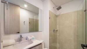 A modern bathroom with a sink, mirror, and glass shower enclosure.