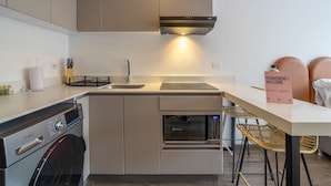A compact kitchen with a washing machine, microwave, and a built-in oven.