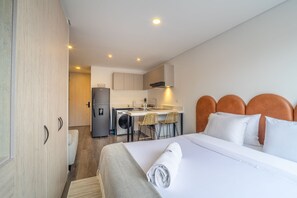 A hotel room with a bed, a neatly made bed, a small kitchenette, and a bathroom. - Valmont by Wynwood House (Bogotá)