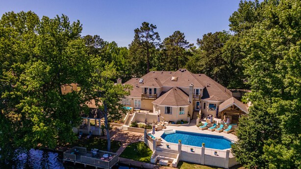 A large house with a swimming pool surrounded by lush greenery.
