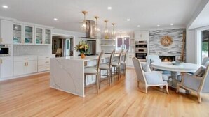 A spacious kitchen with modern appliances, a dining area with chairs, and a fireplace.