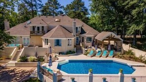 A large house with a swimming pool, covered patio, and a well-maintained garden.