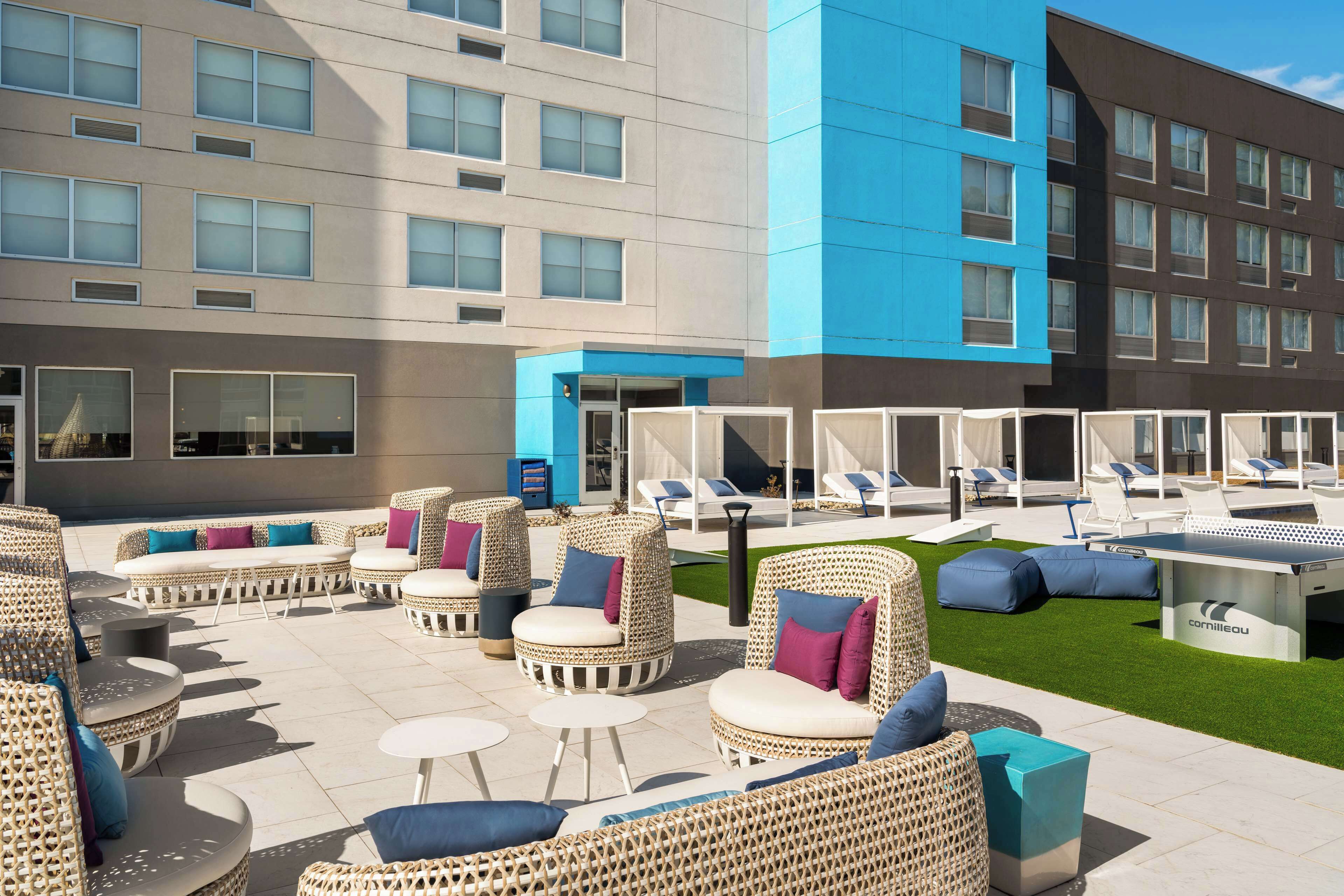 A rooftop lounge area with wicker furniture, a pool table, and a view of the building's exterior.