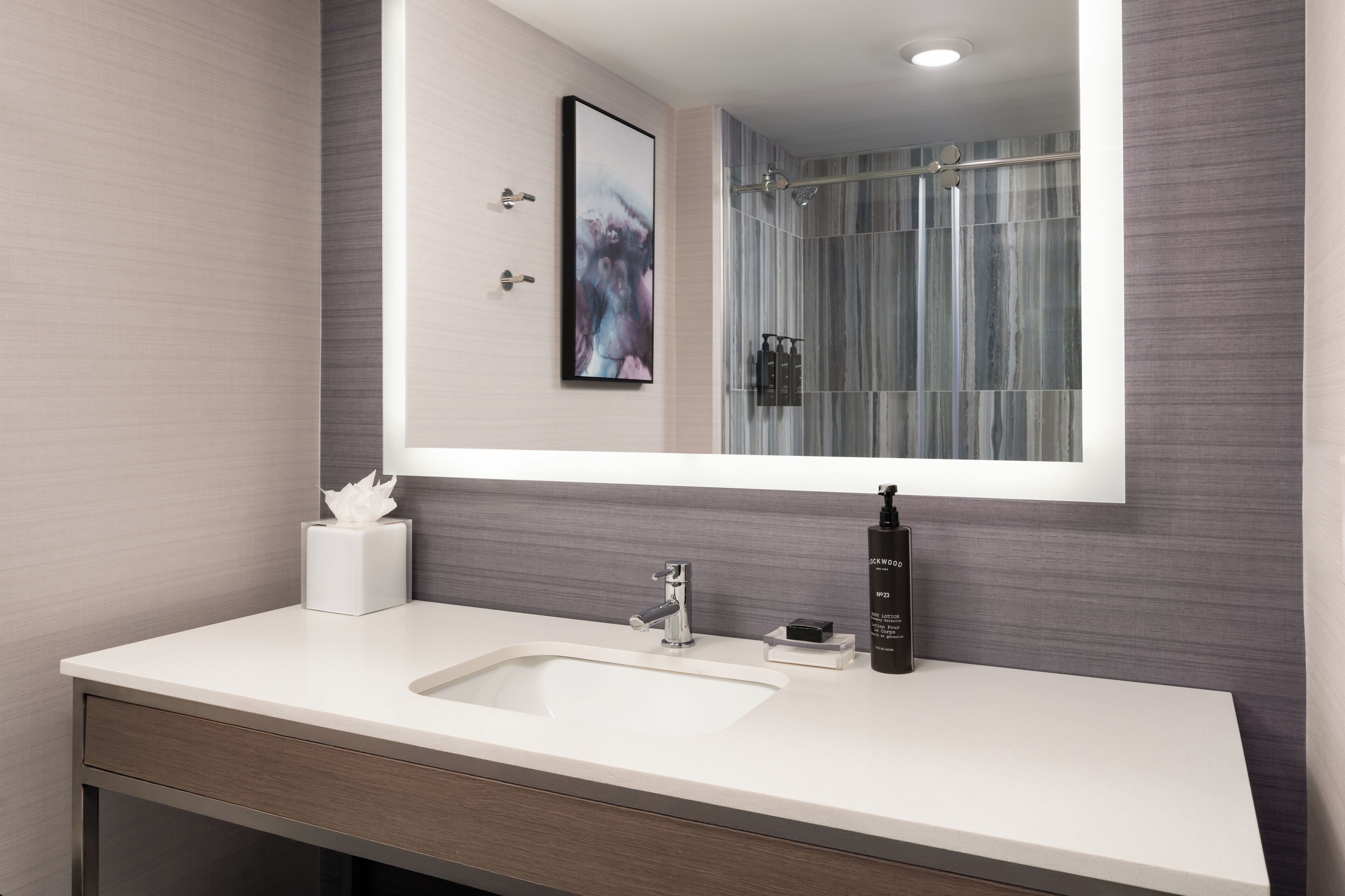 A modern bathroom with a white sink, a large mirror, and a shower with a glass door.