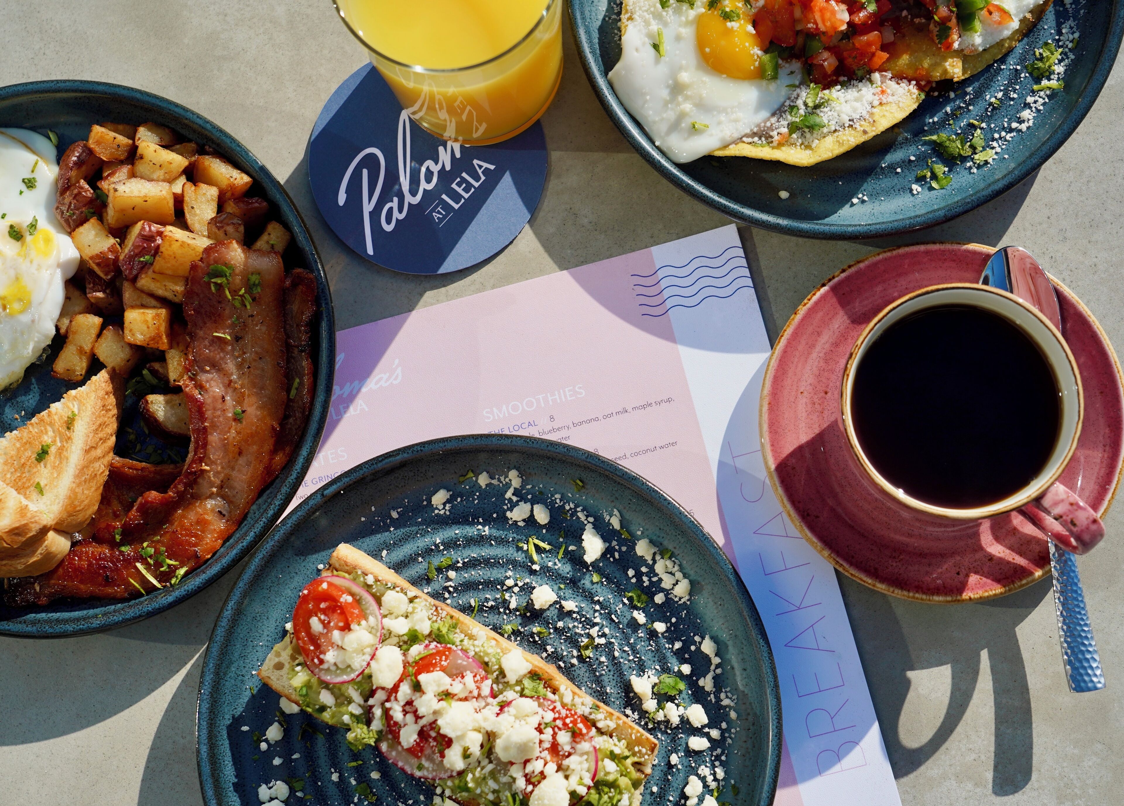 A breakfast table with plates of food, a glass of orange juice, and a cup of coffee.
