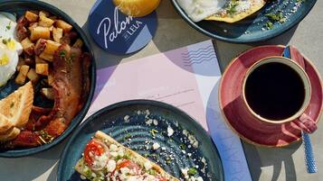 A breakfast table with plates of food, a glass of orange juice, and a cup of coffee.