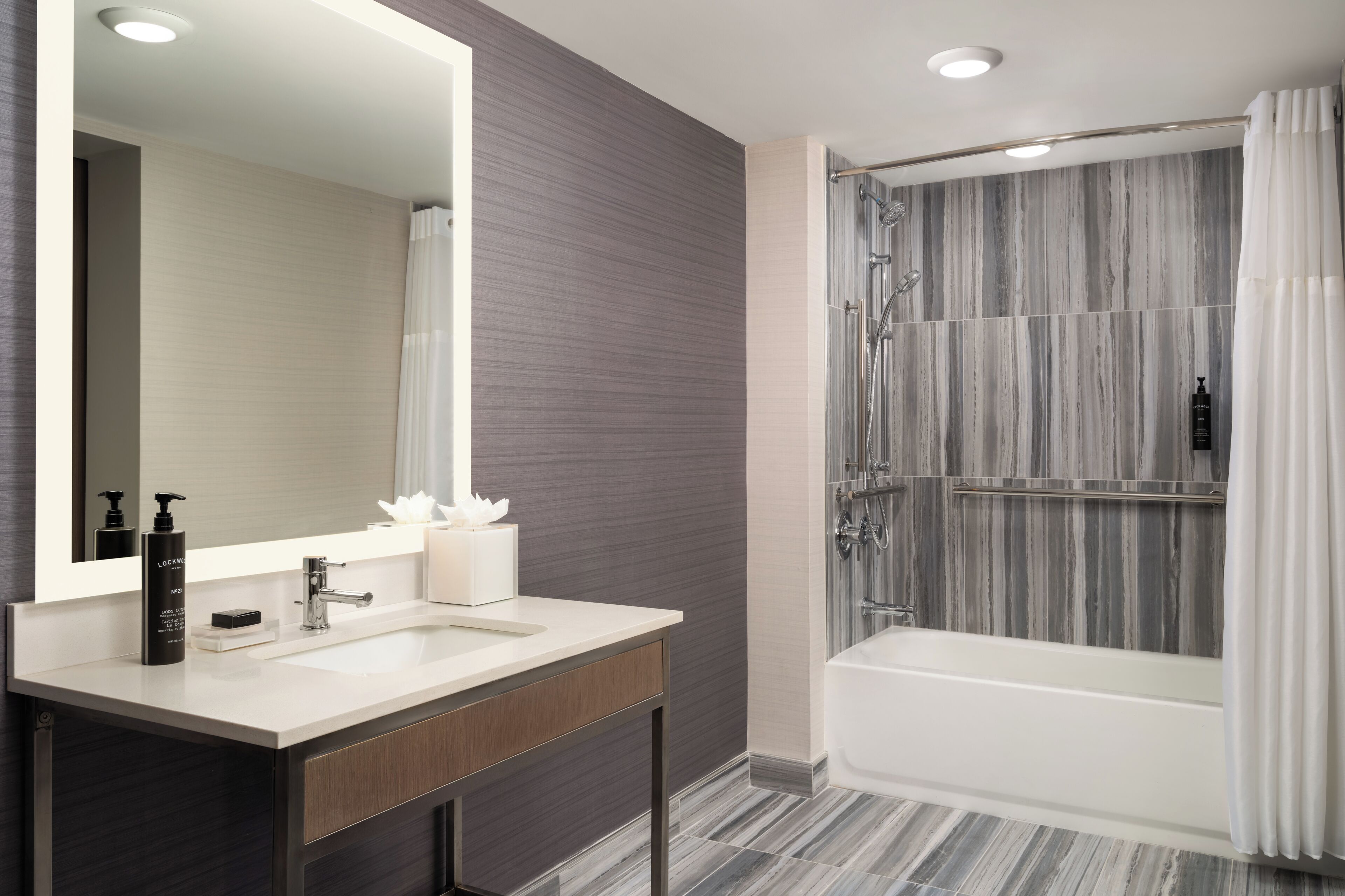 Une salle de bain moderne avec un grand miroir, un lavabo et un espace douche.