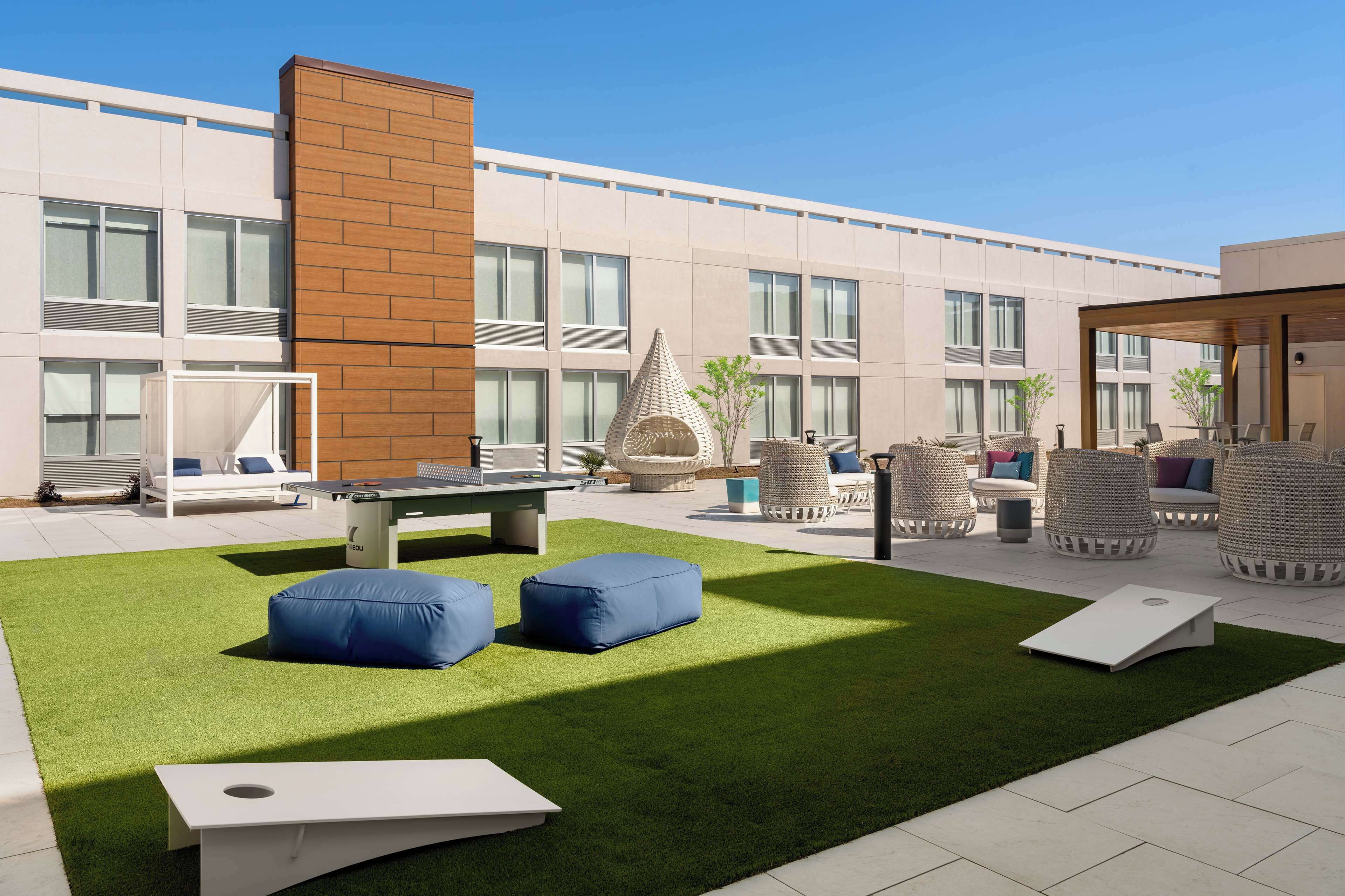 Un patio exterior con césped artificial, zonas de estar y una mesa de billar.