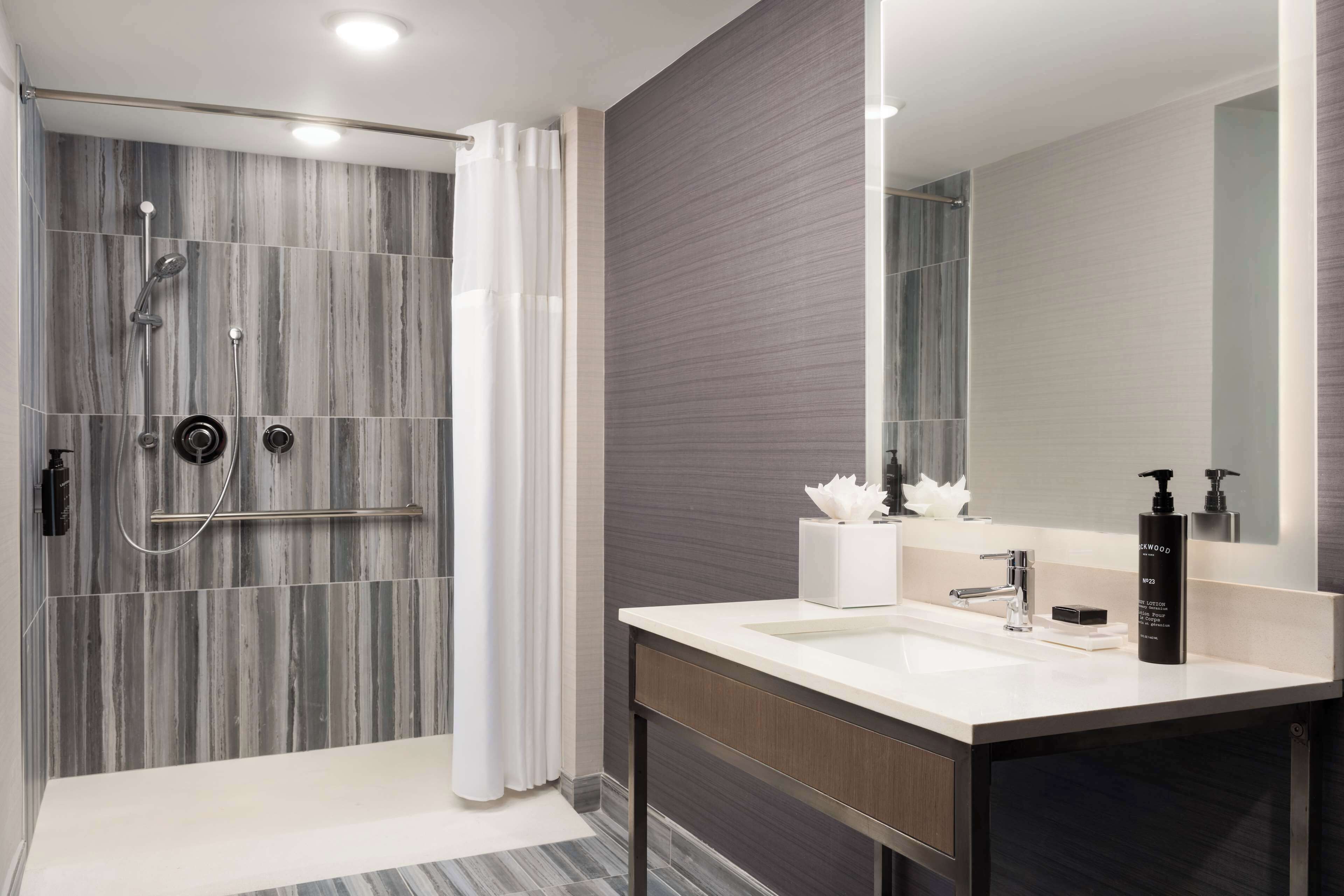 A modern bathroom with a shower, vanity, and large mirror.
