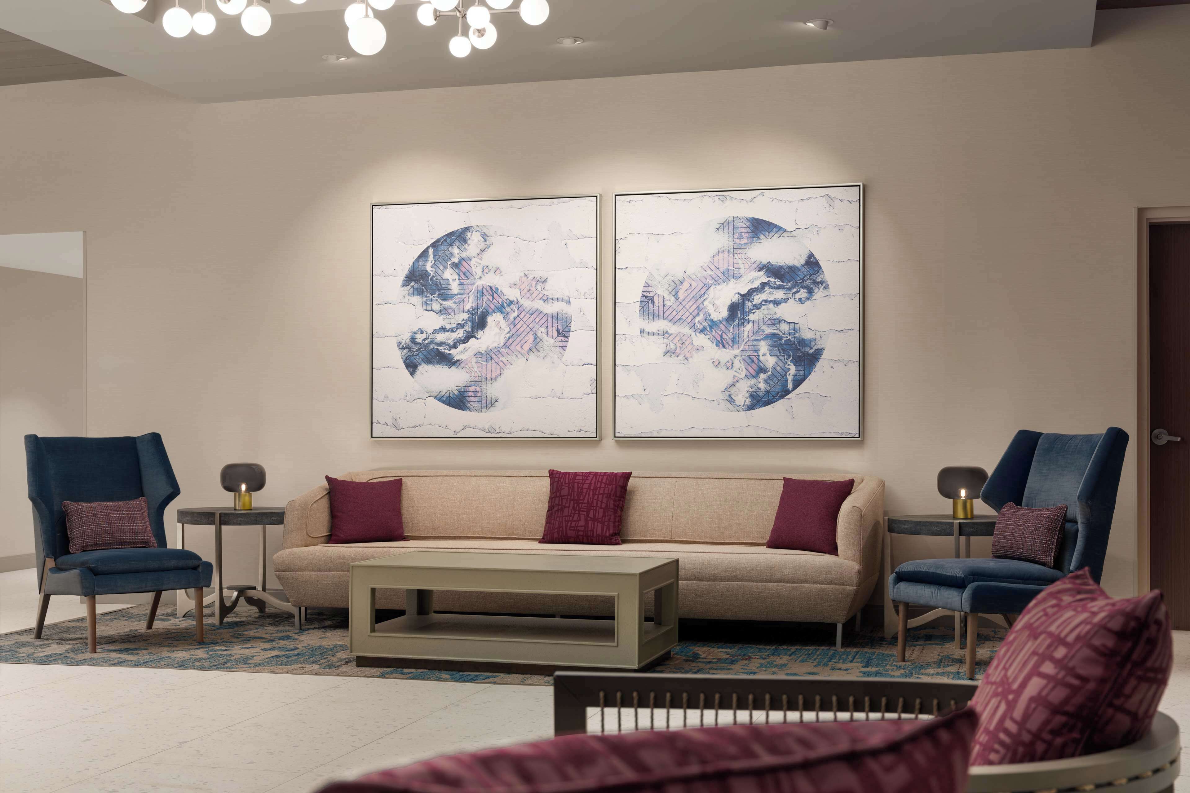 Una sala de estar moderna con un sofá color beige, dos sillones azules, una mesita de centro y arte abstracto en la pared.