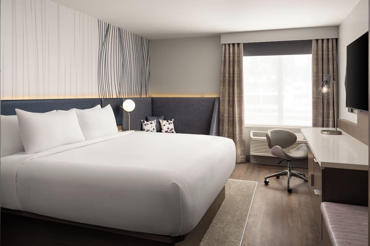 Een moderne hotelkamer met een groot bed, een bureau en een flatscreen televisie.