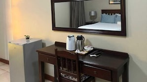A hotel room with a desk, chair, and a large mirror. There is a small refrigerator, a coffee maker, and a kettle on the desk. - Ikhutse Guest House (Kanye)