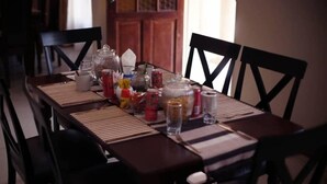 A dining table set with various food items and condiments, surrounded by chairs. - Ikhutse Guest House (Kanye)