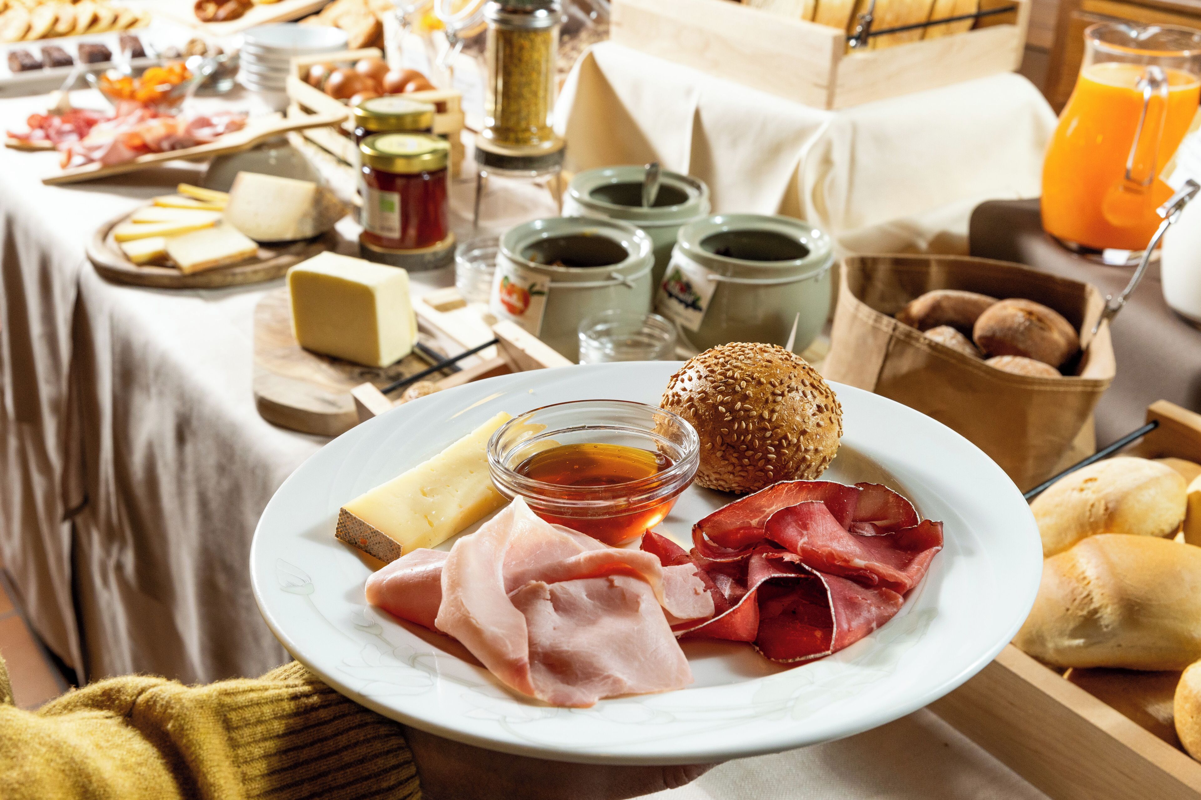 A breakfast spread with cheese, ham, bread, and condiments on a table.