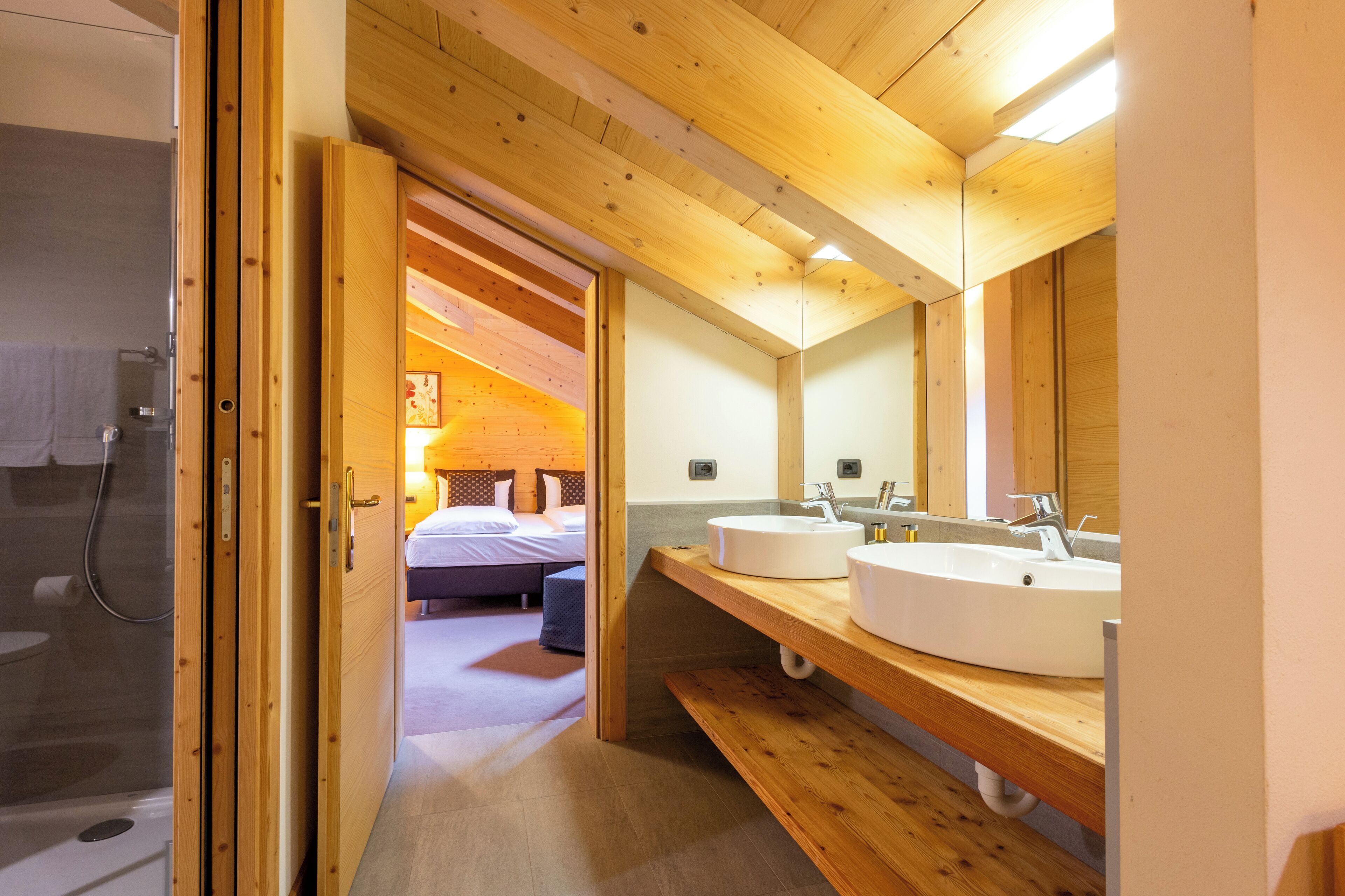 A wooden interior with a bathroom, a bed, and a sink.