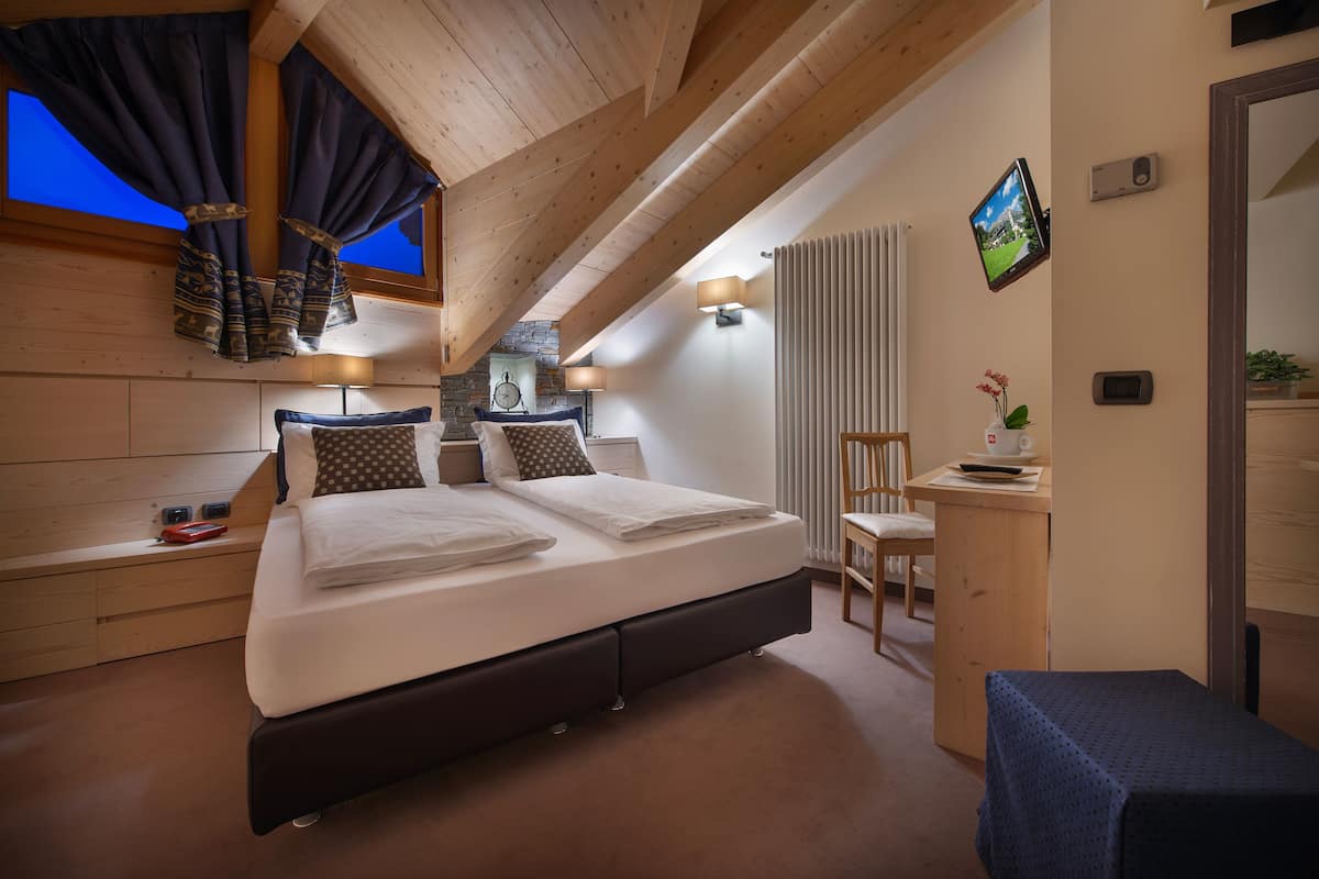 A bedroom with a bed, bedside tables, a desk, and a chair.