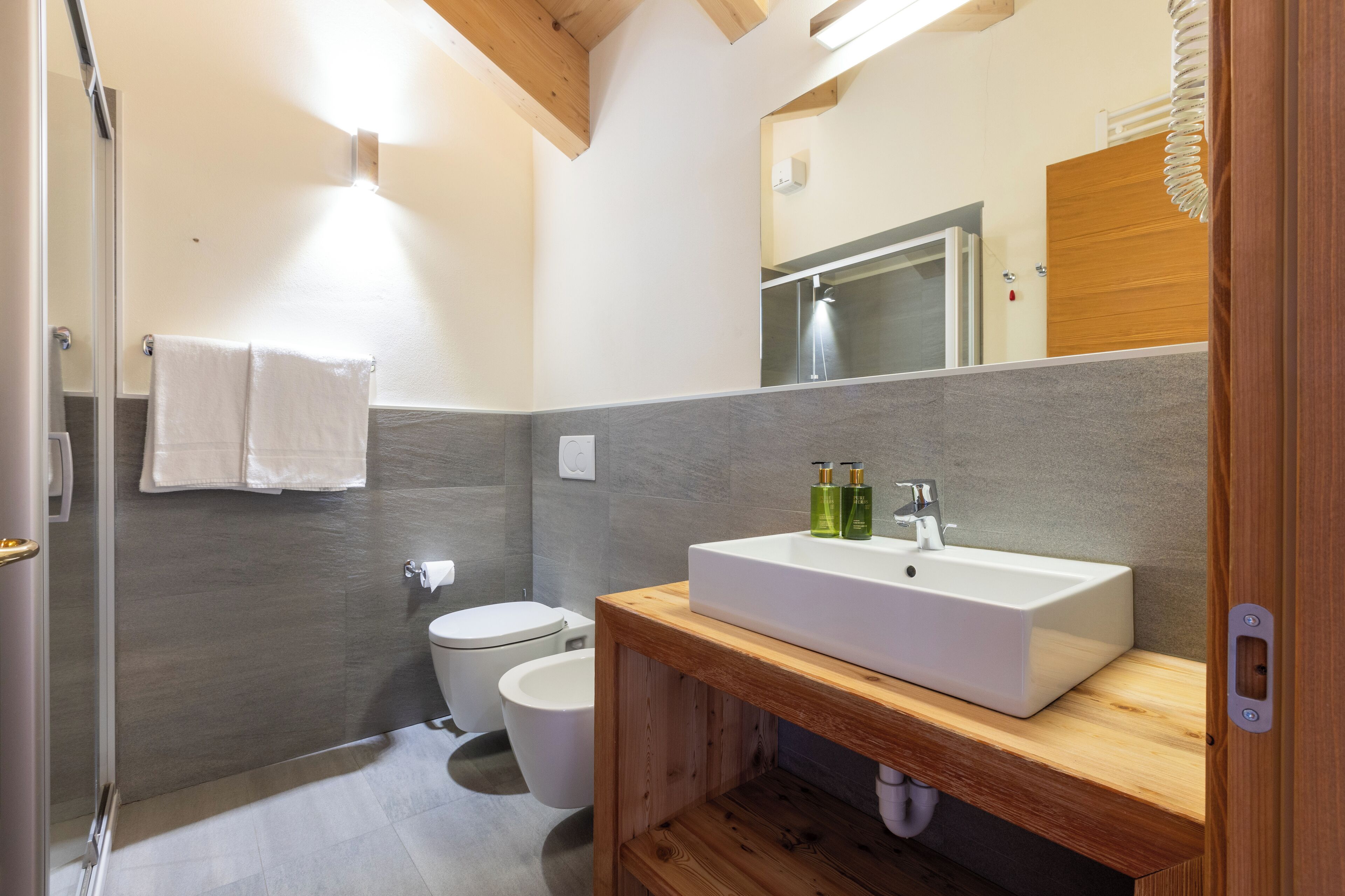 A modern bathroom with a wooden vanity, a large mirror, and a white sink.
