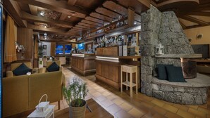Un interior acogedor con muebles de madera, una chimenea de piedra y una zona de bar.