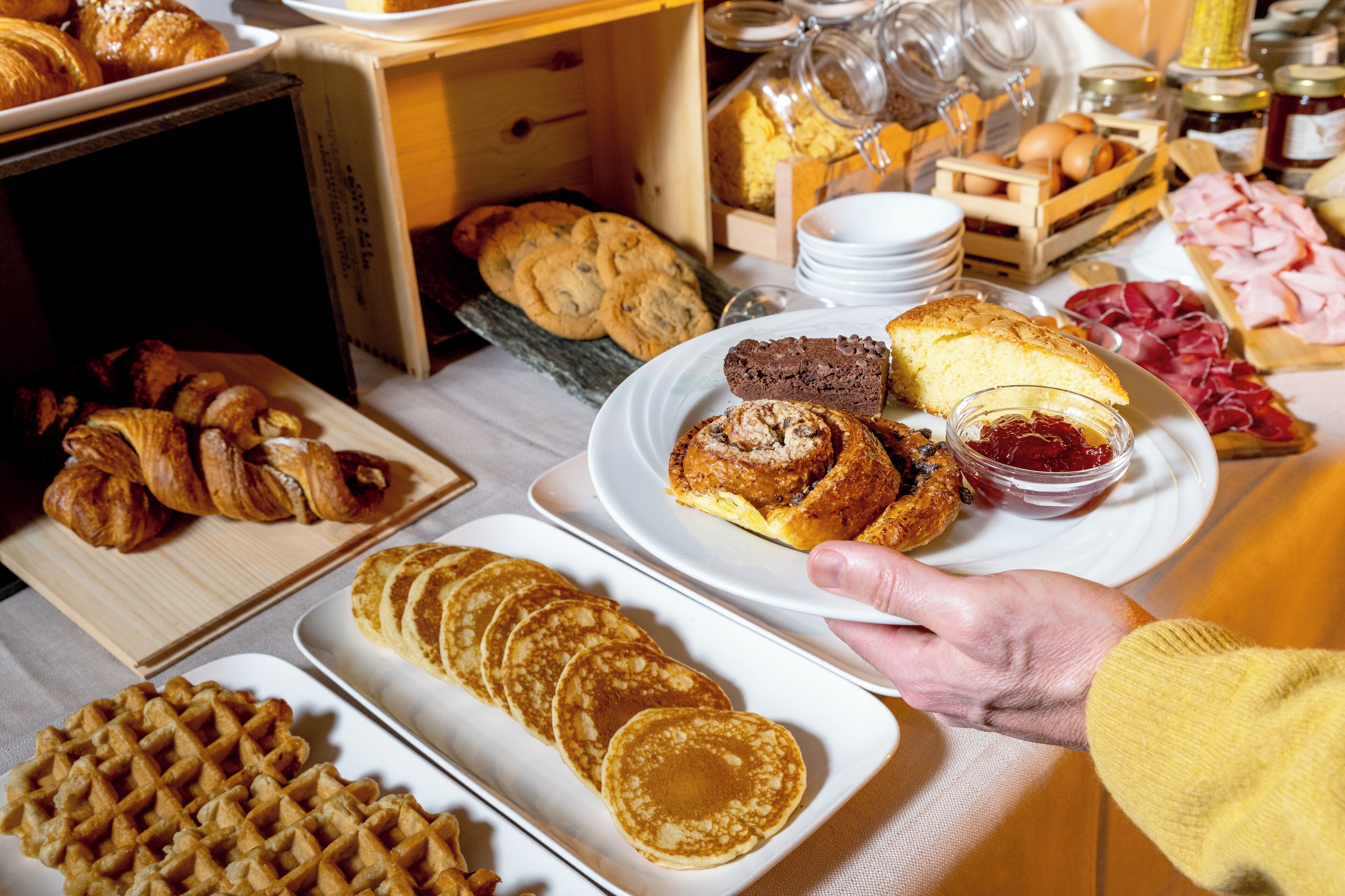Een ontbijtbuffet met gebak, wafels en verschillende toppings.