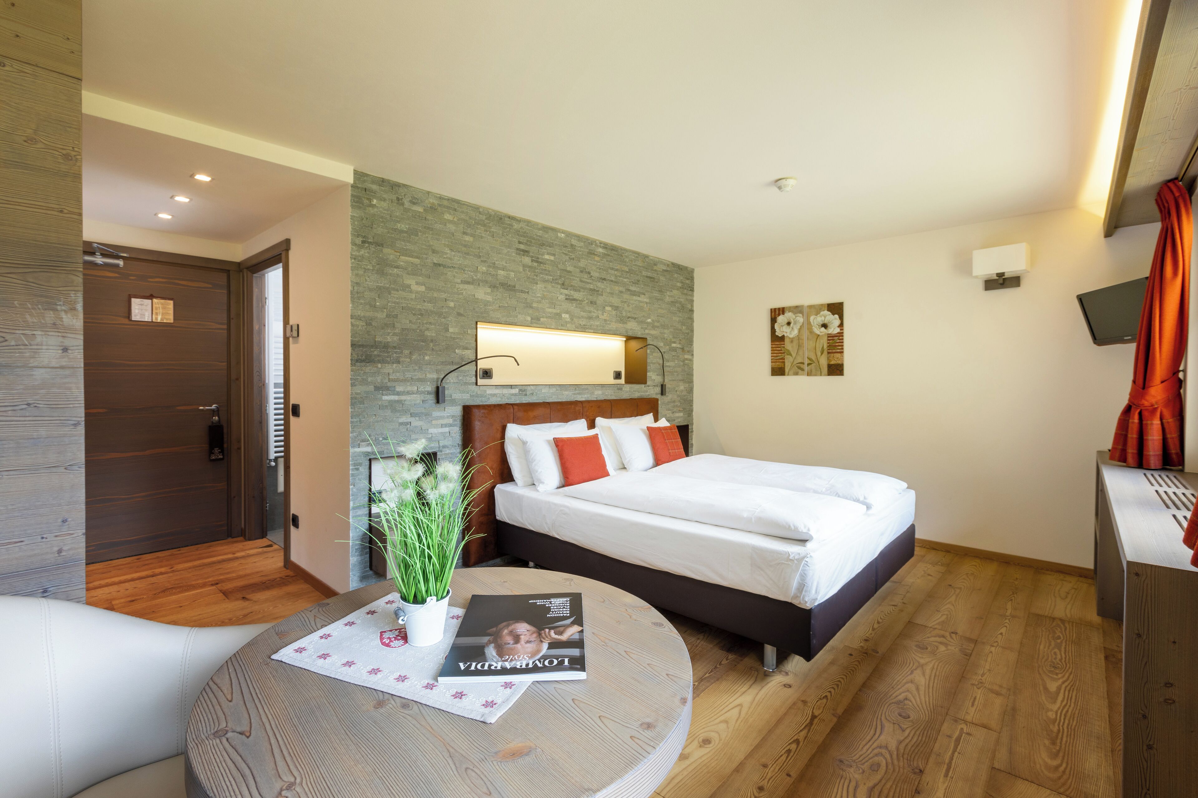 Una habitación de hotel moderna con una cama, una mesita de noche y una mesa redonda con una revista.