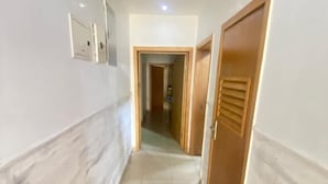 A hallway with tiled flooring, a ceiling light, and a door with a window. - Samcel Shortlet Apartment (Lagos)