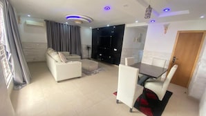 A modern living room with a sofa, dining table, and chairs. - Samcel Shortlet Apartment (Lagos)