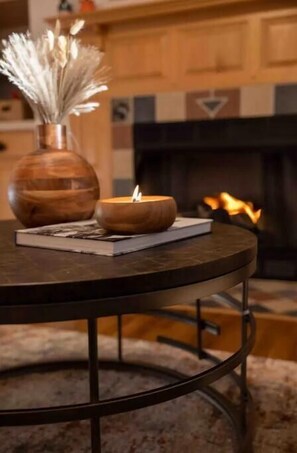 A round table with a candle, a book, and a vase with dried flowers.