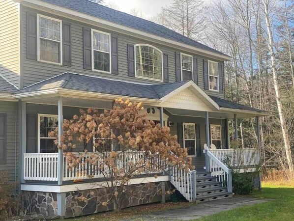 Une maison à deux étages, dotée d’un porche couvert et de fondations en pierre.