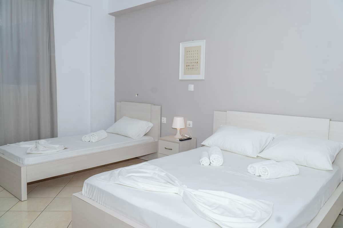 A hotel room with two beds, a nightstand with a lamp, and a framed calendar on the wall.