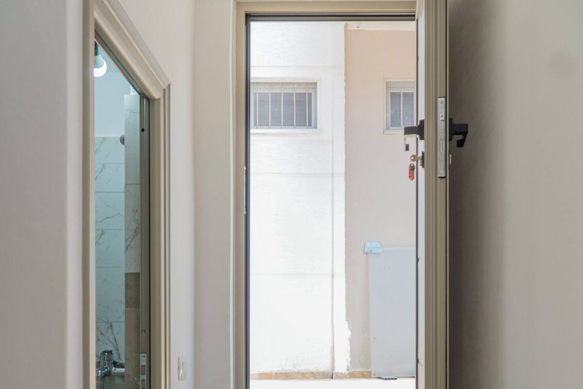 A staircase leading to a door with a glass panel, a view of a building outside, and a tiled floor.
