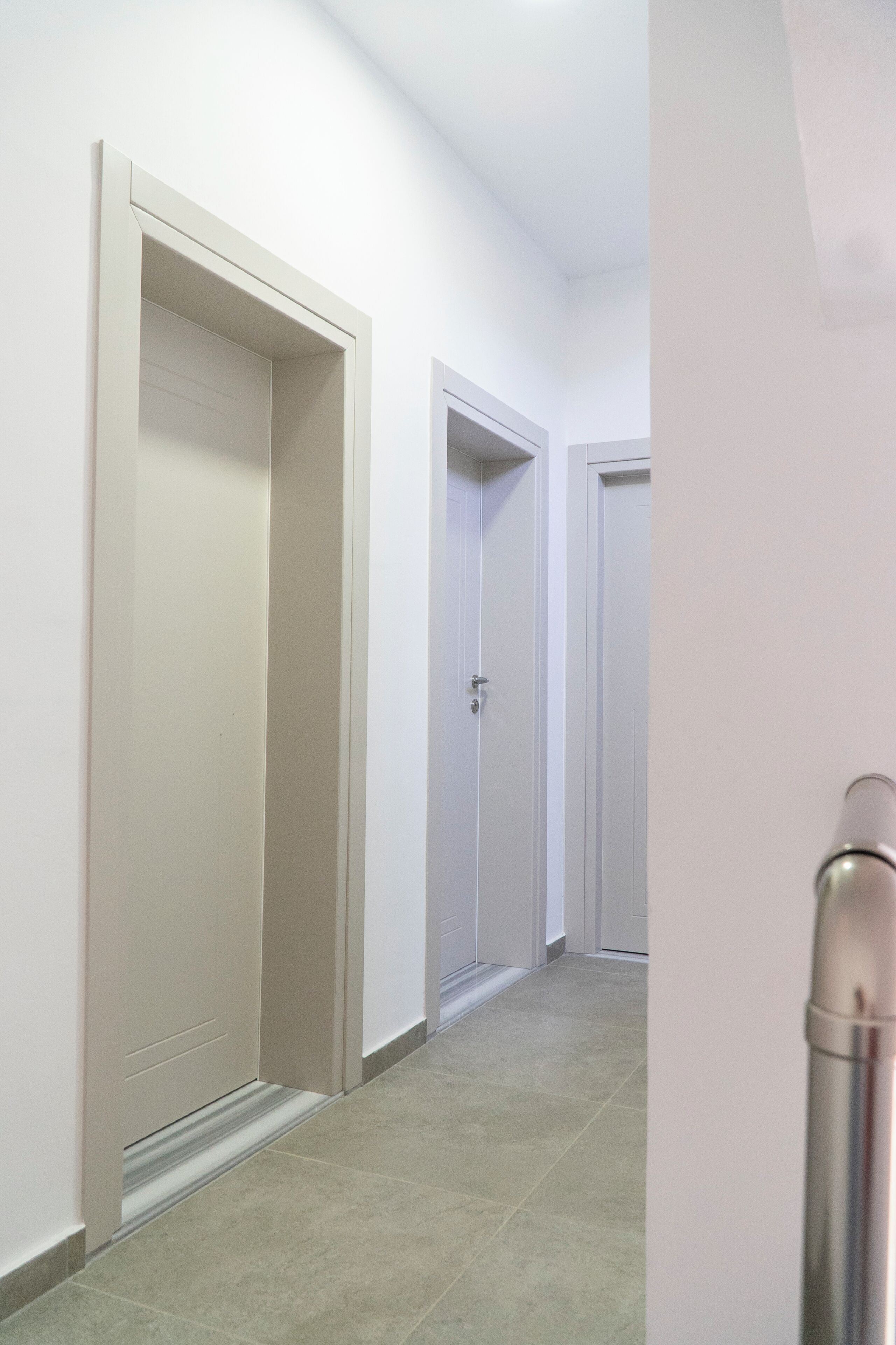 A hallway with closed doors and a metallic object on the right.