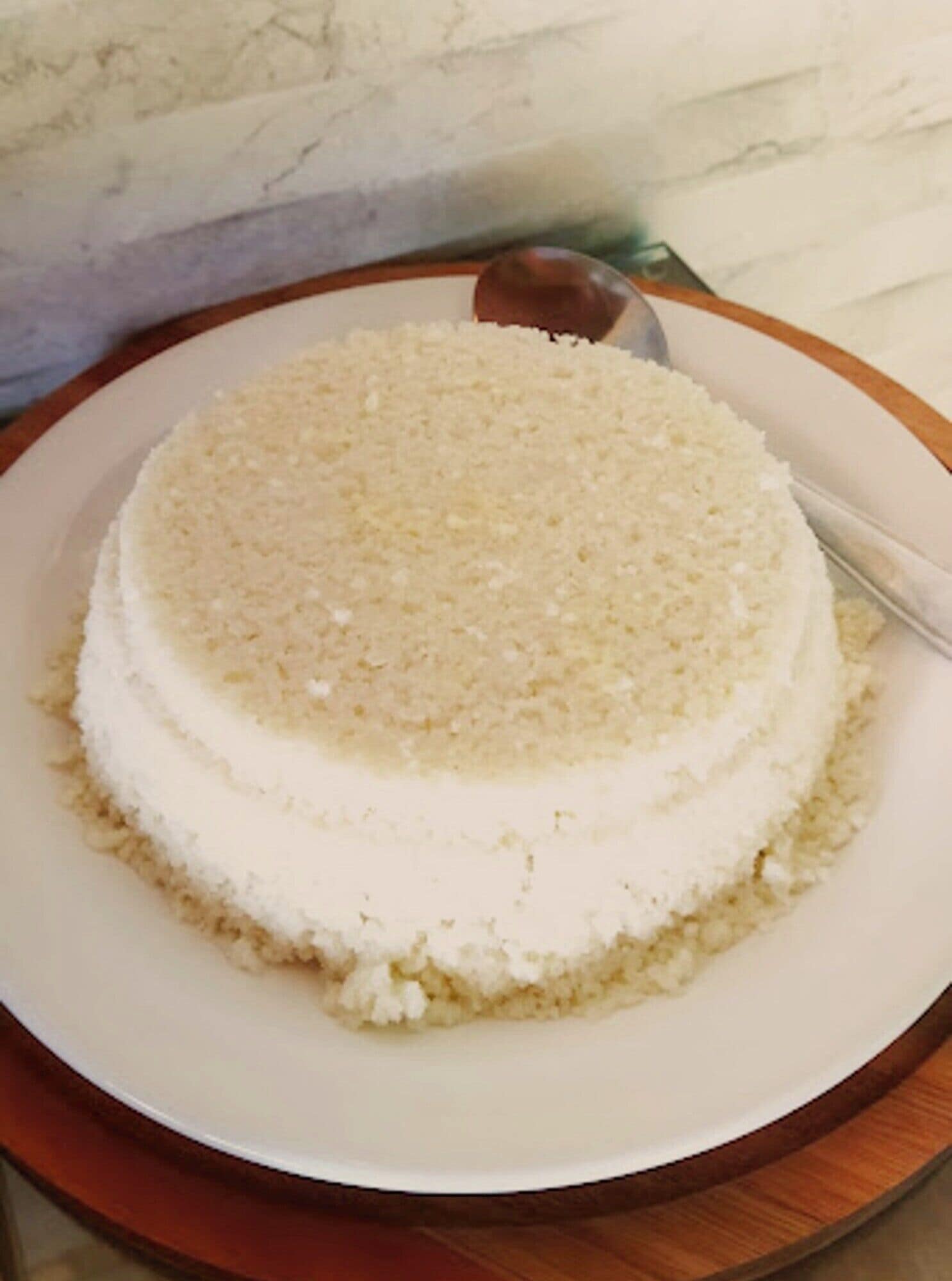 A round cake with a white frosting on a white plate.
