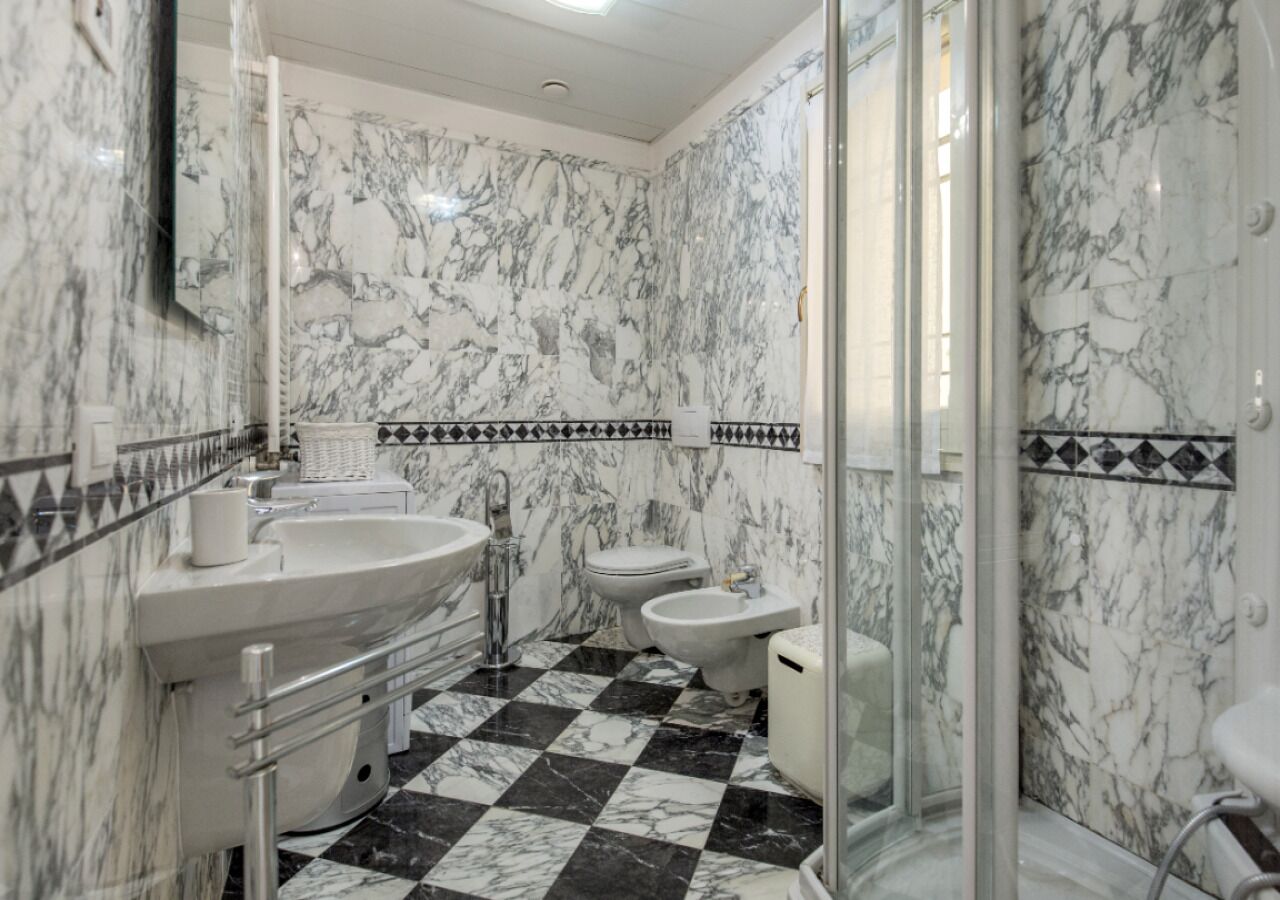 A bathroom with a marble floor, a sink, a toilet, and a bidet.