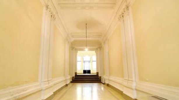 A long, narrow hallway with a staircase at the end leading to a bright room.