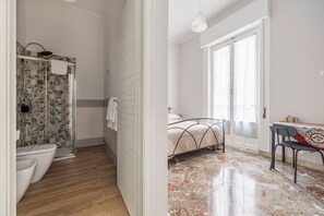 Kylpyhuone, jossa on suihku, wc ja kuviollinen seinä.