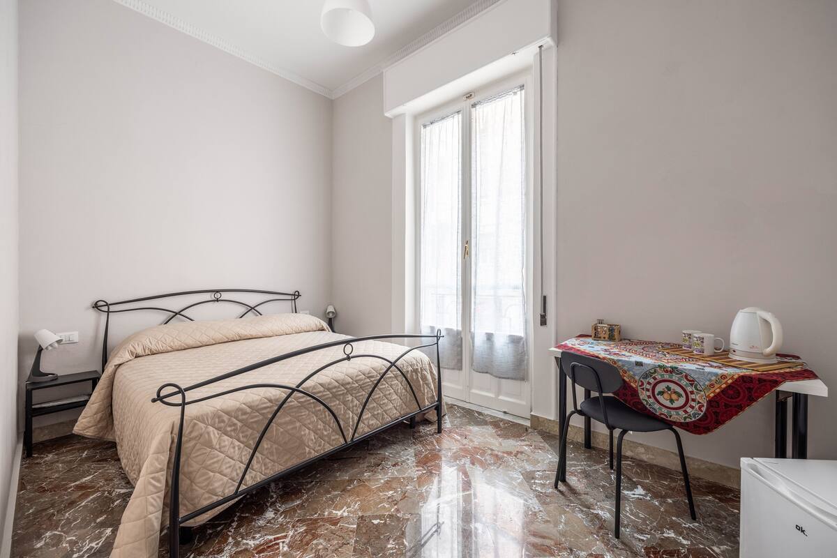 Un dormitorio con cama, mesita de noche, lámpara y una mesa con mantel.
