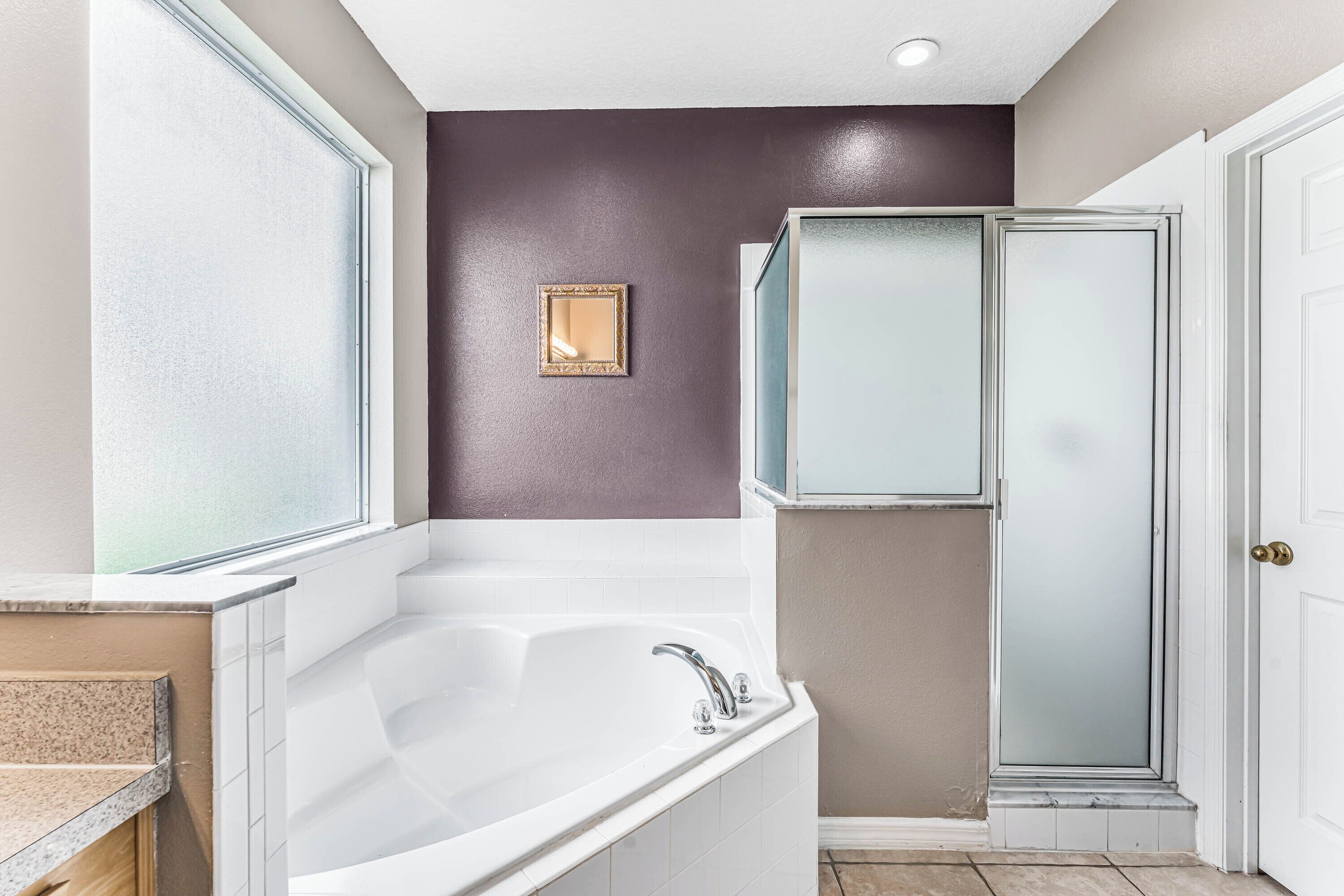 A bathroom with a bathtub, a shower, and a vanity with a mirror.
