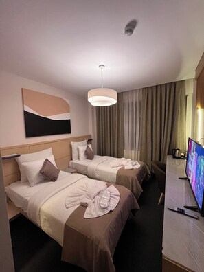 Une chambre d’hôtel avec deux lits, une télévision et un bureau équipé d’une bouilloire.