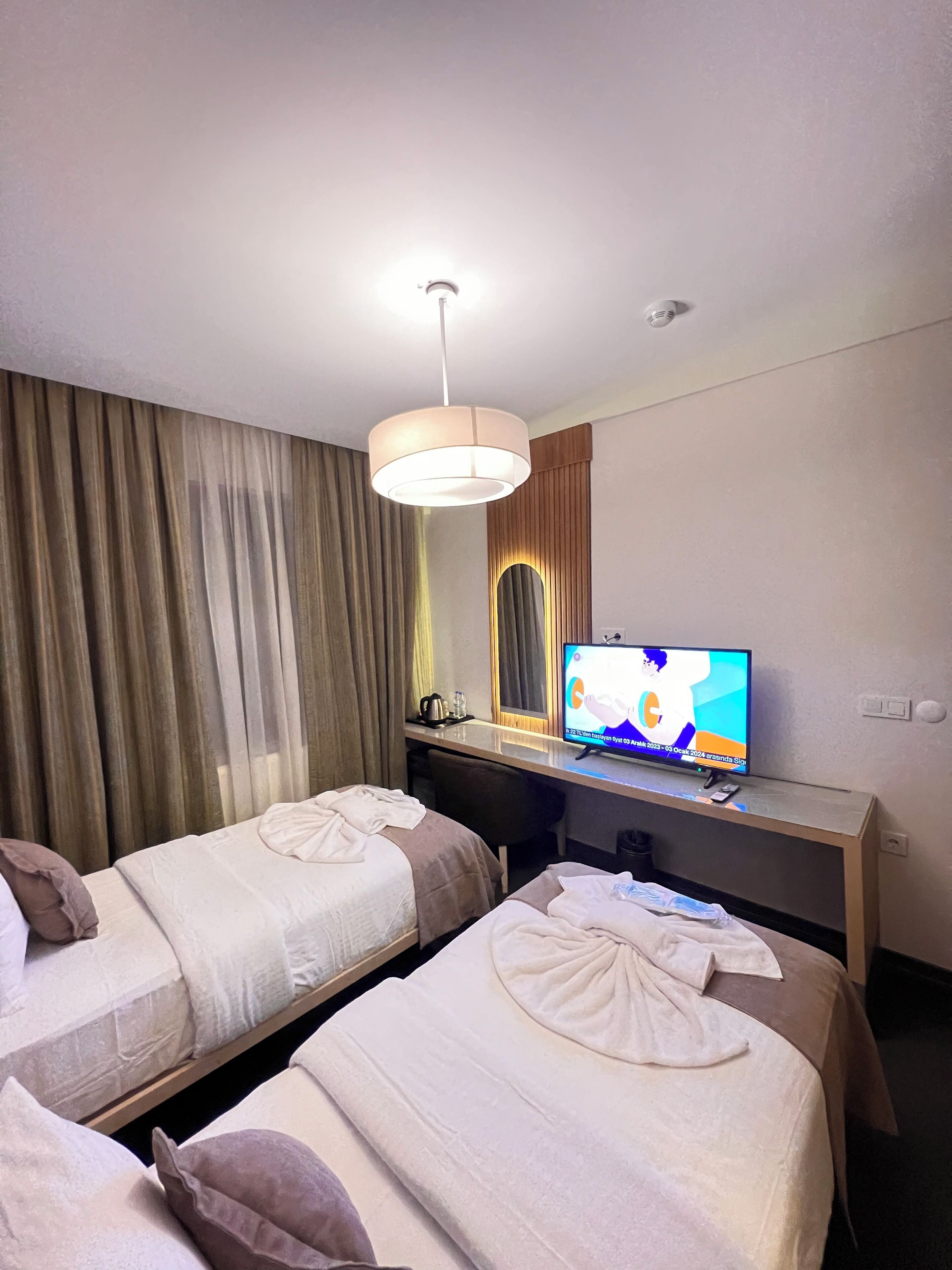 Una habitación de hotel con dos camas, televisión, escritorio y espejo.